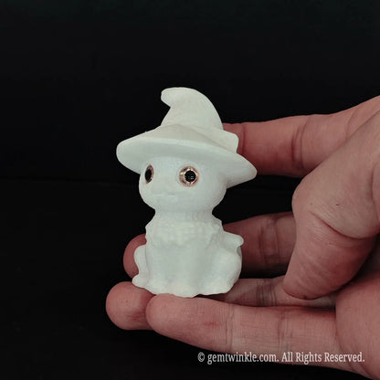 A human hand holding a 6cm white marble witch cat figurine to demonstrate its pocket size and smooth polished texture