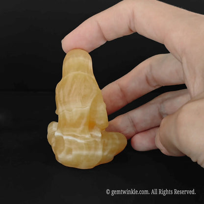 back view of a golden yellow calcite seated holy mother figurine showing smooth stone finish