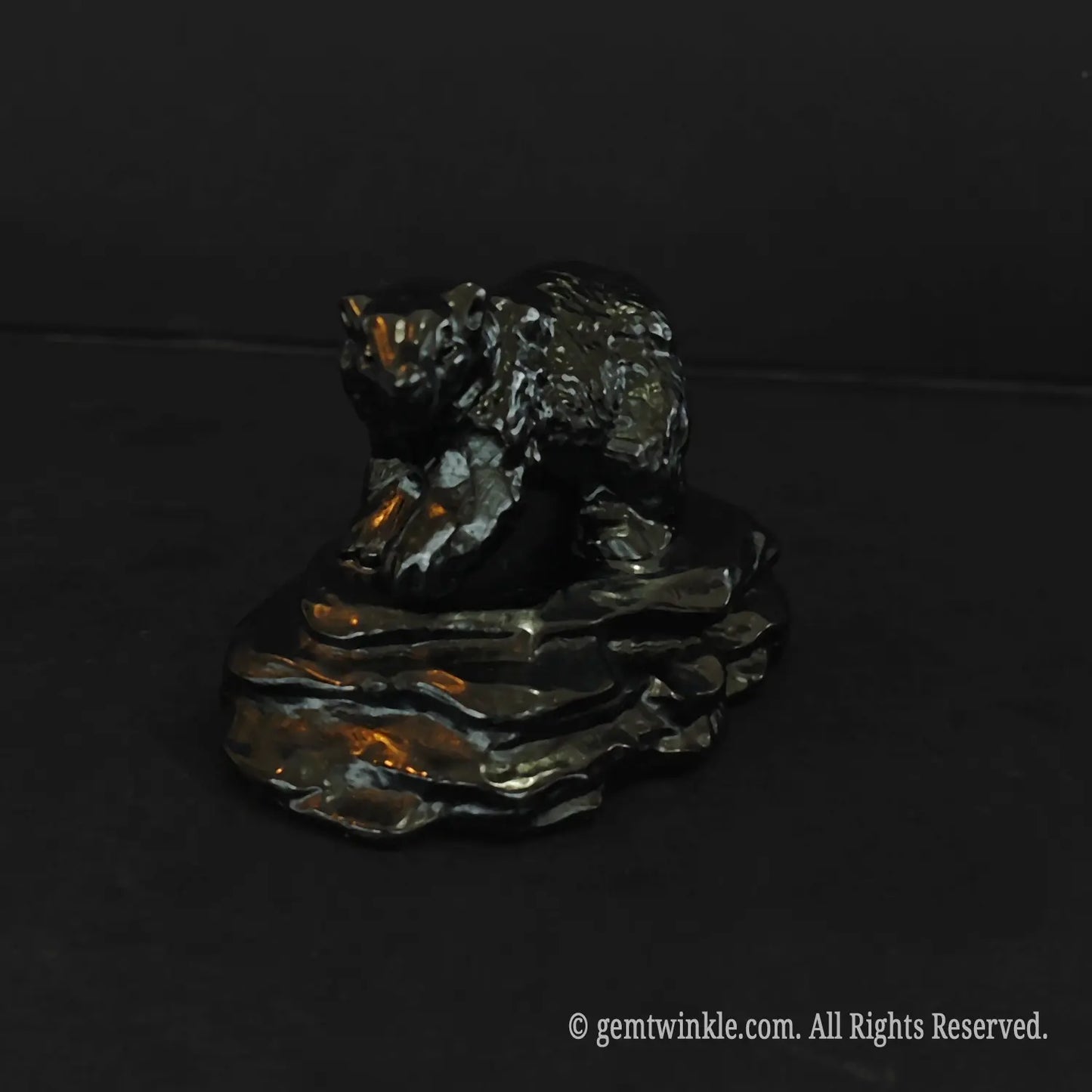 front view of an eight centimeter black obsidian bear figurine on a stone base