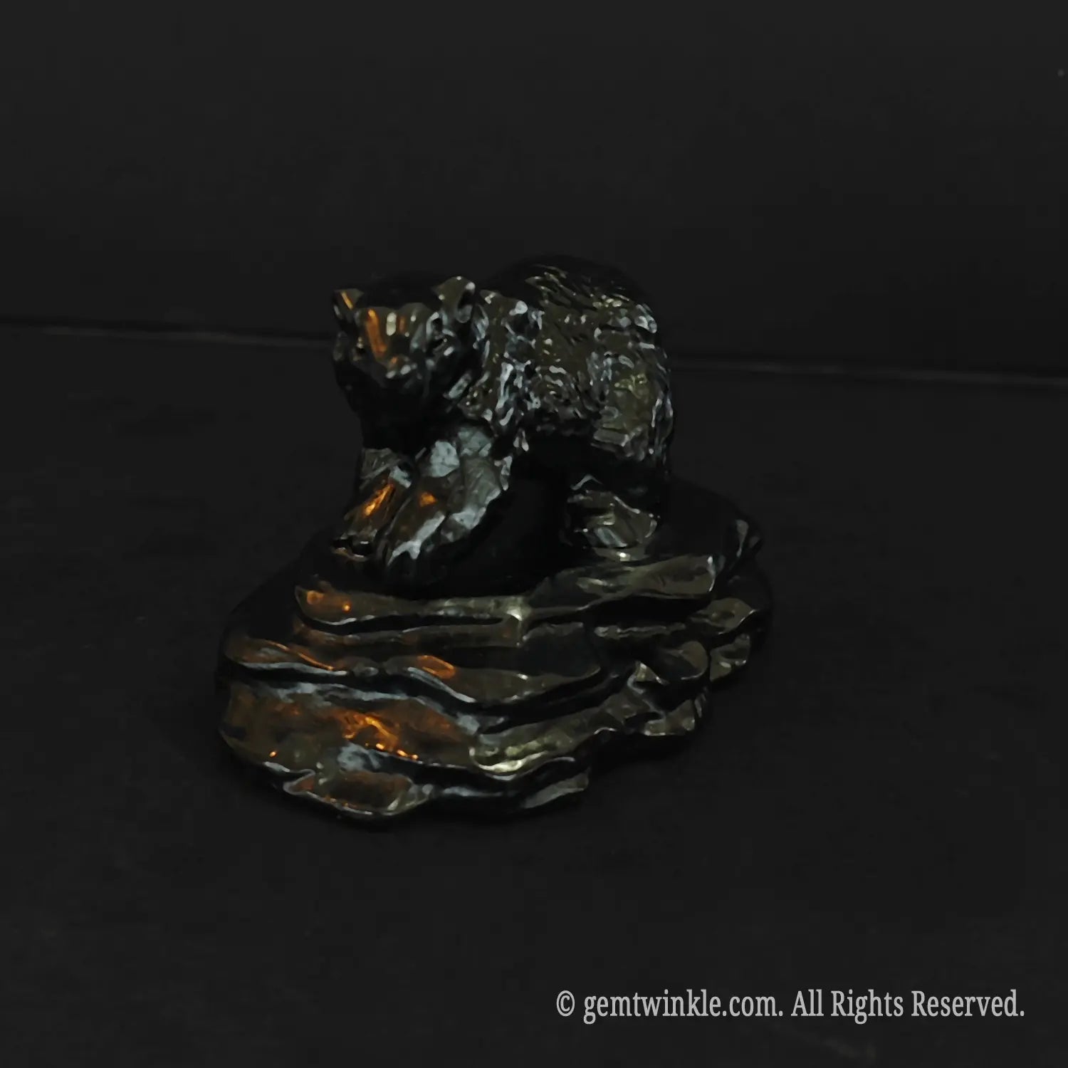 front view of an eight centimeter black obsidian bear figurine on a stone base