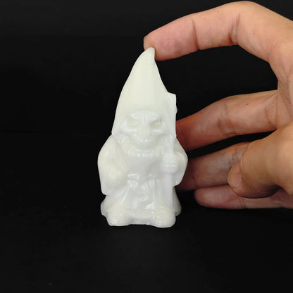 hand holding a large eight centimeter white marble gnome carving with pointy hat