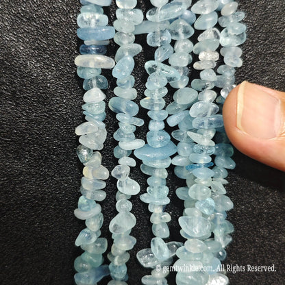 Close up of multi strands of acid-washed aquamarine 5-10mm irregular light blue chips