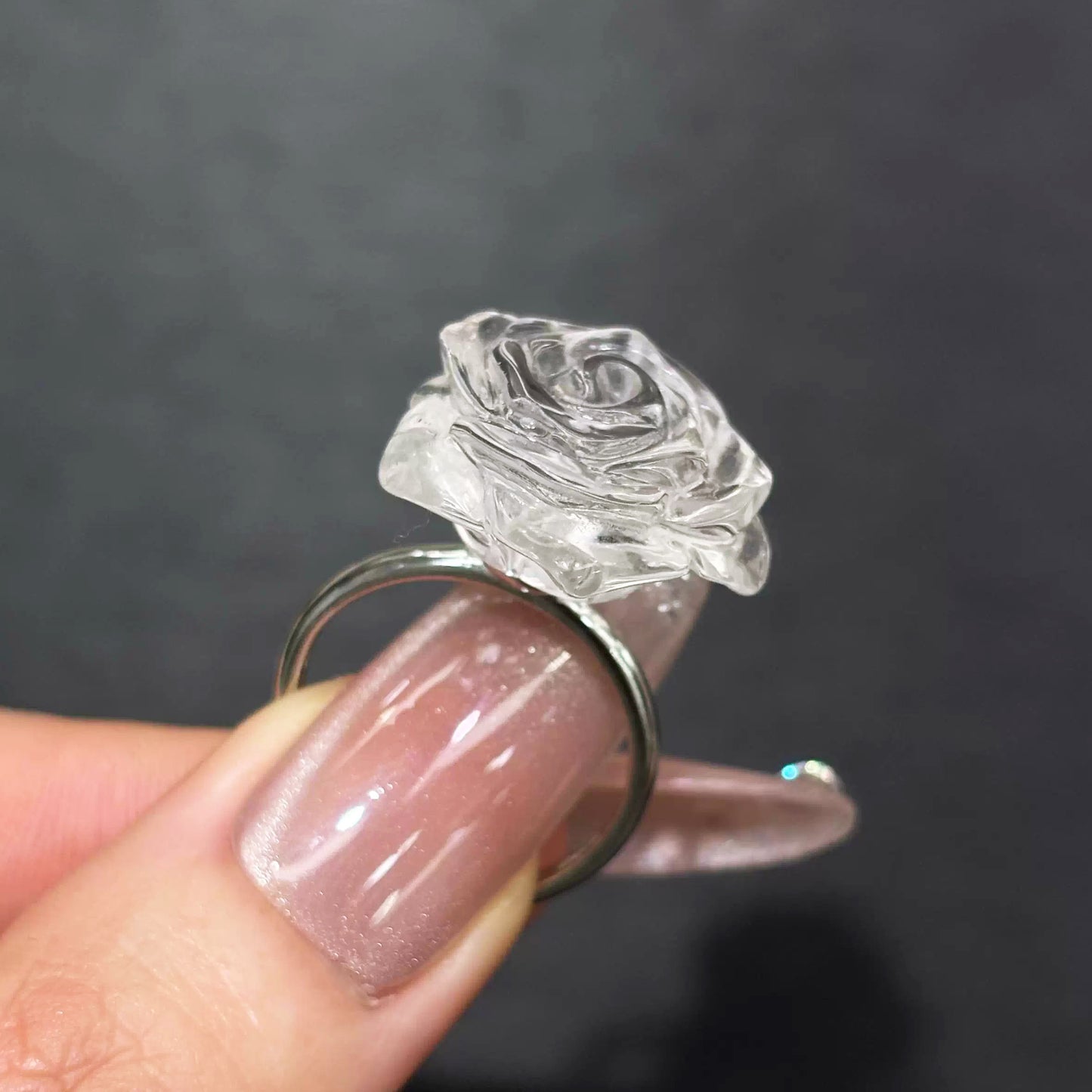Close-up of clear quartz rose ring held in hand, revealing S925 silver adjustable opening and petal texture