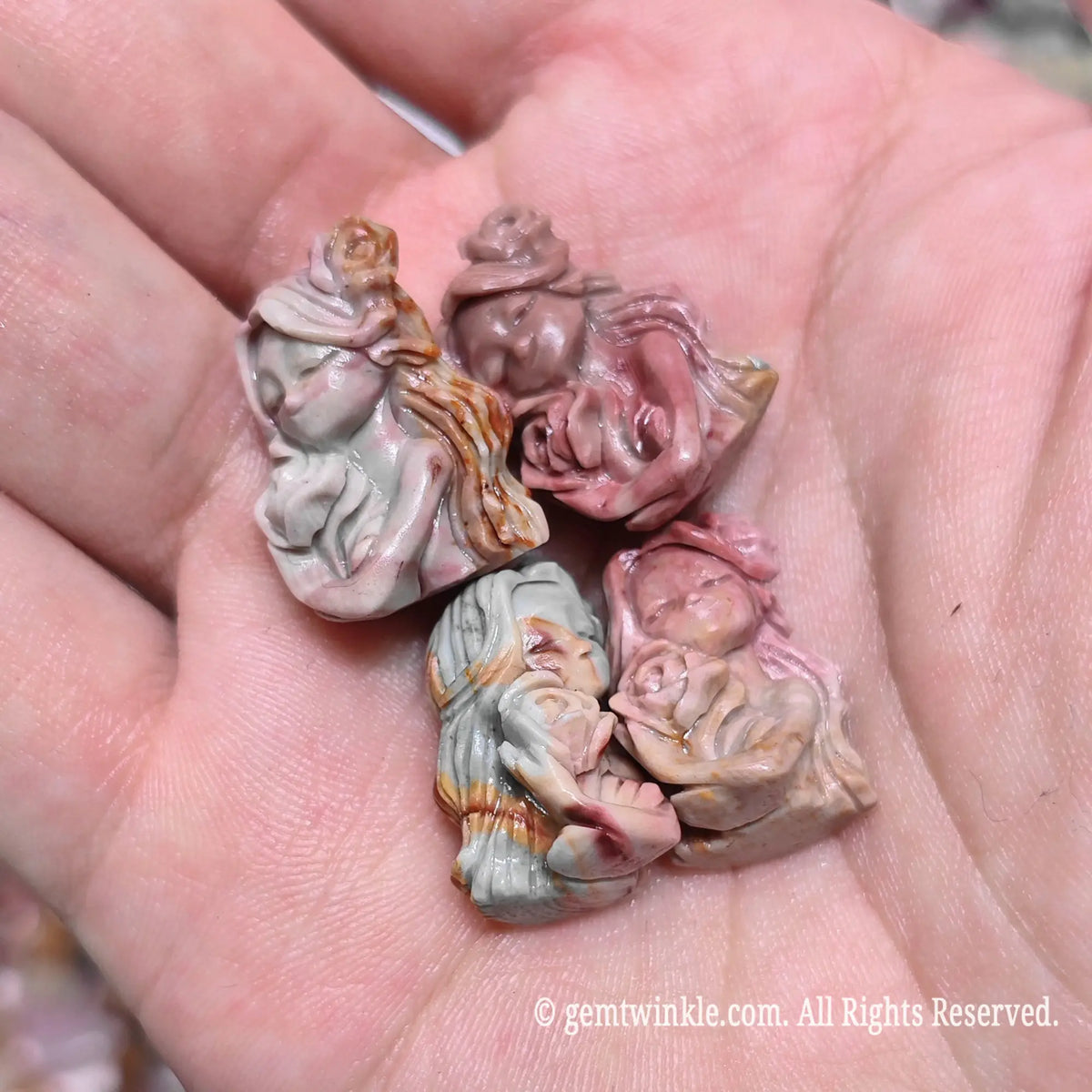 Palm holding multiple natural Alxa agate rose maiden mini sculptures showing varied earthy pink and green tones