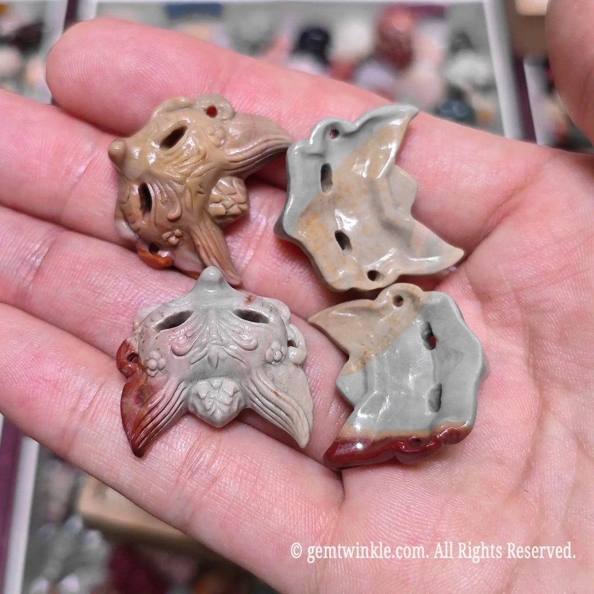 Palm holding multiple natural Alxa agate fox mask mini sculptures showing detailed hollow eye carvings and varied earth tones
