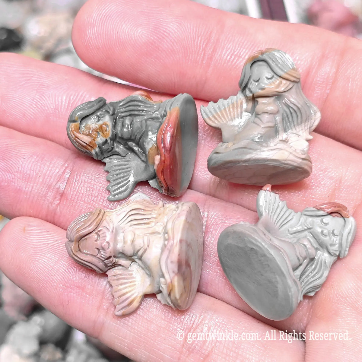 Palm displaying multiple natural Alxa agate mermaid figurines showing stable flat base and detailed tail scales
