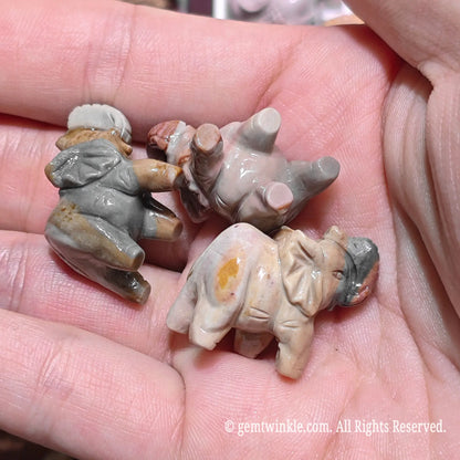 Palm displaying multiple miniature Alxa agate elephant carvings showcasing varied natural desert color patterns