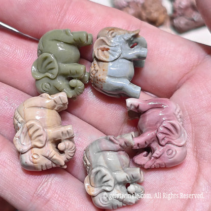 Palm holding multiple natural Alxa agate elephant mini carvings showcasing rose pink sage green and gray color patterns