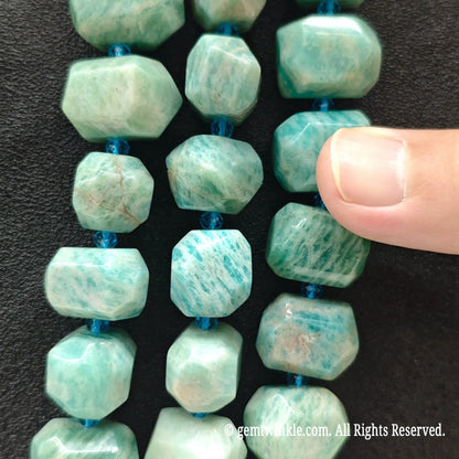 Close up perspective of multiple natural green amazonite freeform faceted bead strands showing silky luster