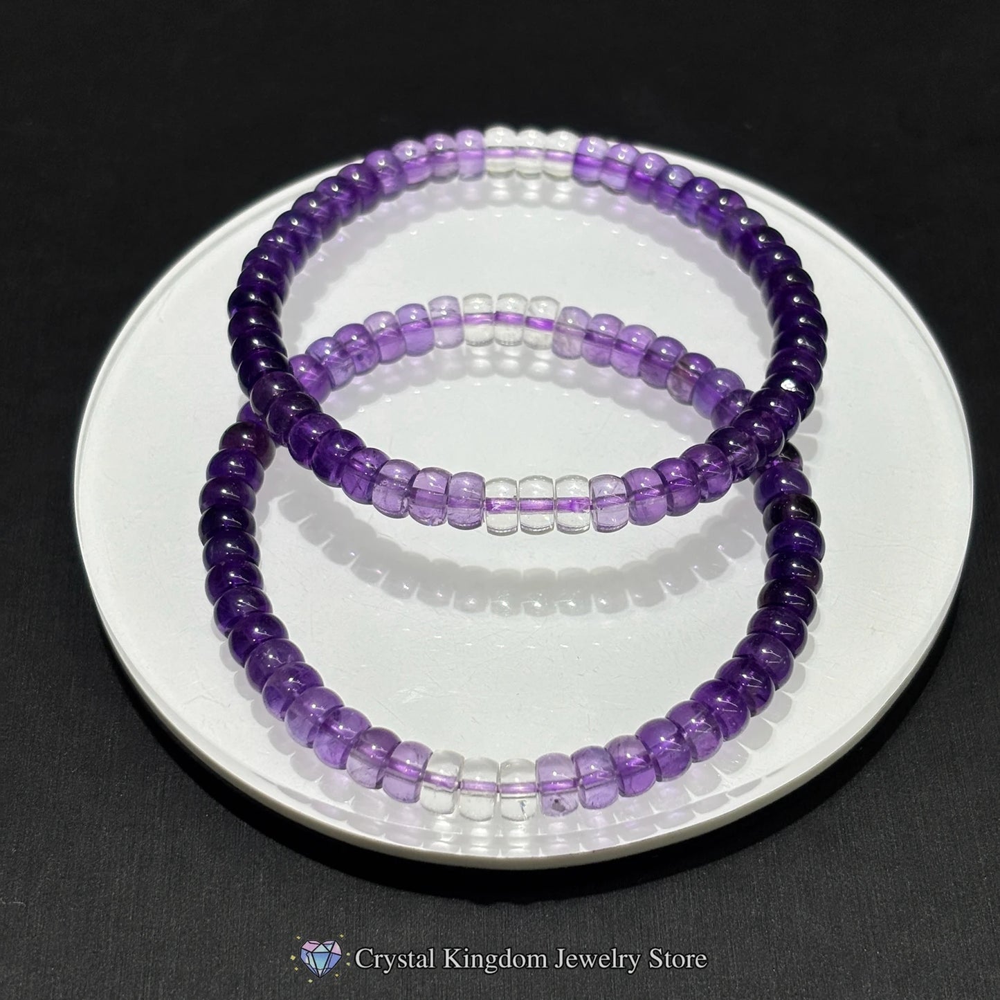 Two purple beaded bracelets on a white plate with a black background