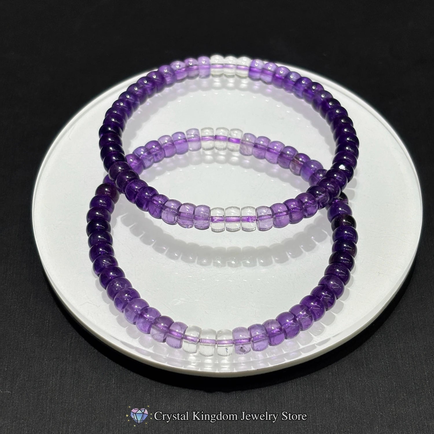 Two purple beaded bracelets on a white plate with a black background