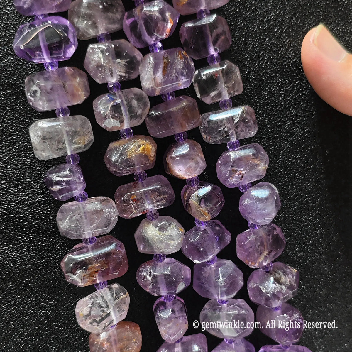 Hand showing large irregular amethyst phantom quartz loose beads highlighting translucent purple tones and light phantom inclusions