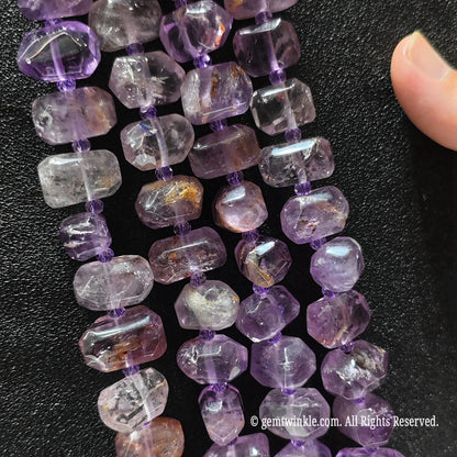 Hand showing large irregular amethyst phantom quartz loose beads highlighting translucent purple tones and light phantom inclusions