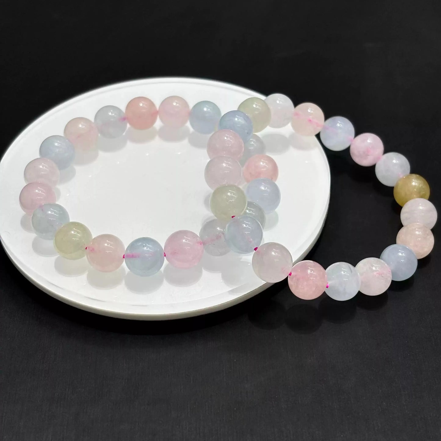 Morganite bracelet arranged in overlapping circles on white dish, highlighting bead uniformity and gentle color gradient.