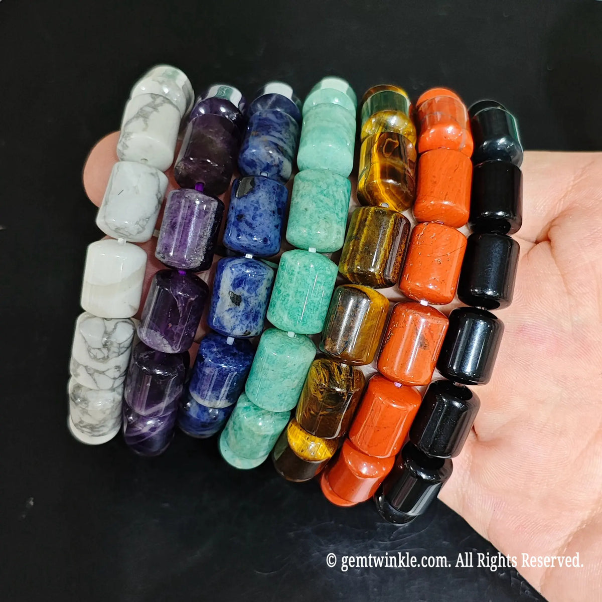 Assorted Chakra Stone Barrel Bead Strands Close Up on Hand