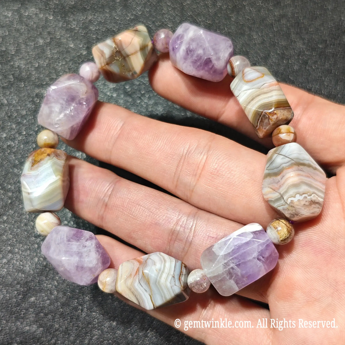 Hand displaying a natural amethyst and striped banded agate faceted nugget bracelet under natural light