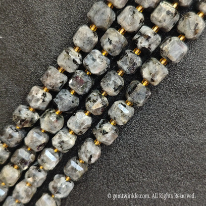 Multiple parallel strands of natural black arfvedsonite soft-tumbled cube beads viewed from distance