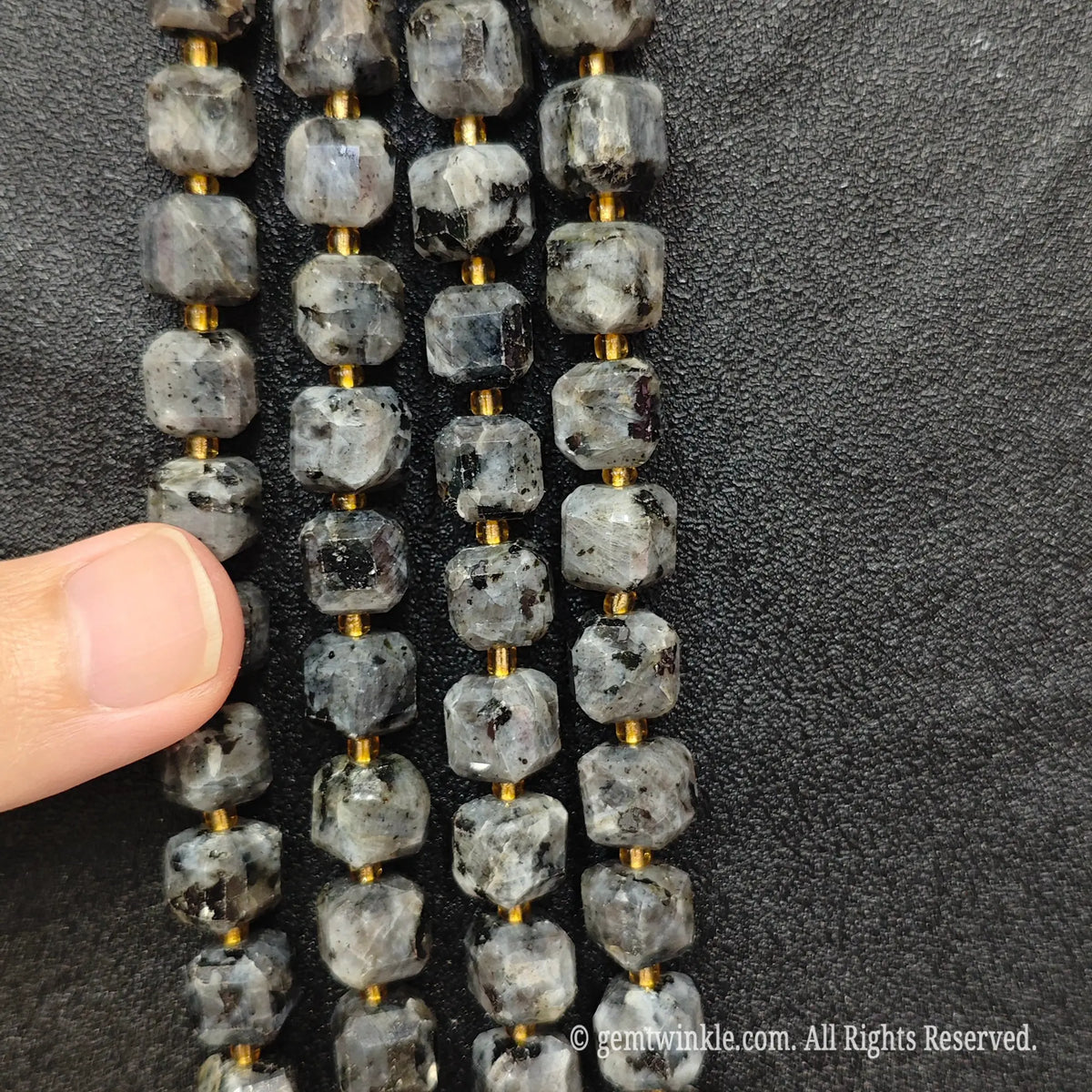 Detailed macro view of natural black arfvedsonite geometric cube beads showcasing dark flash inclusions and matrix