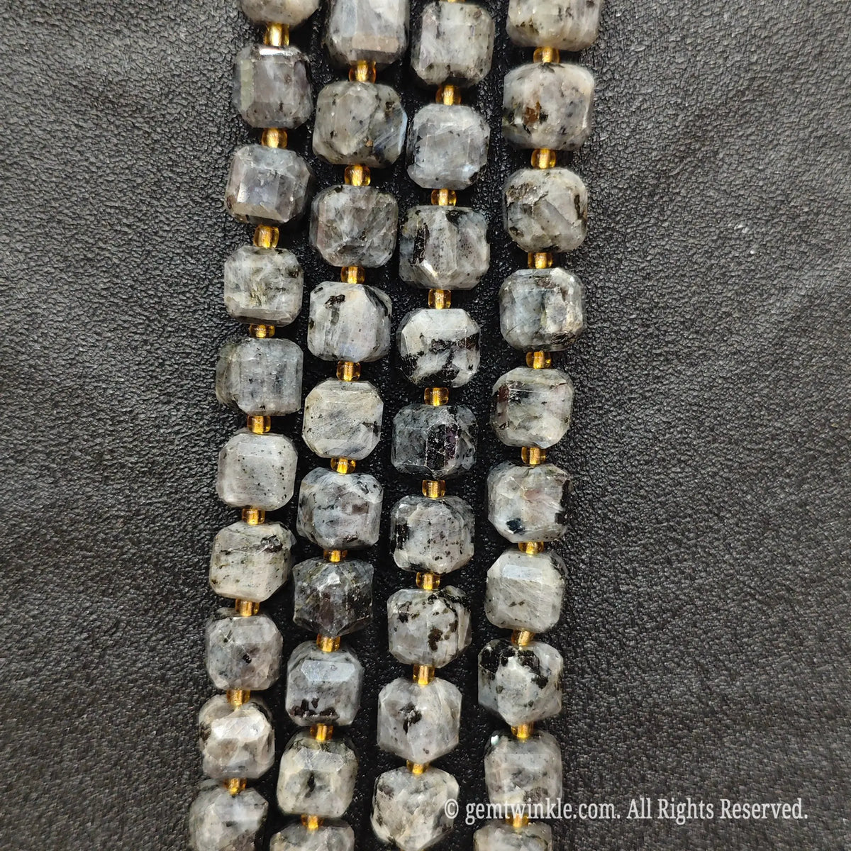 Fingers holding natural black arfvedsonite soft square gemstone block beads to show scale and proportion