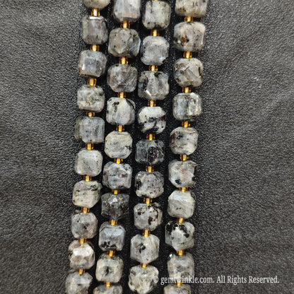 Fingers holding natural black arfvedsonite soft square gemstone block beads to show scale and proportion