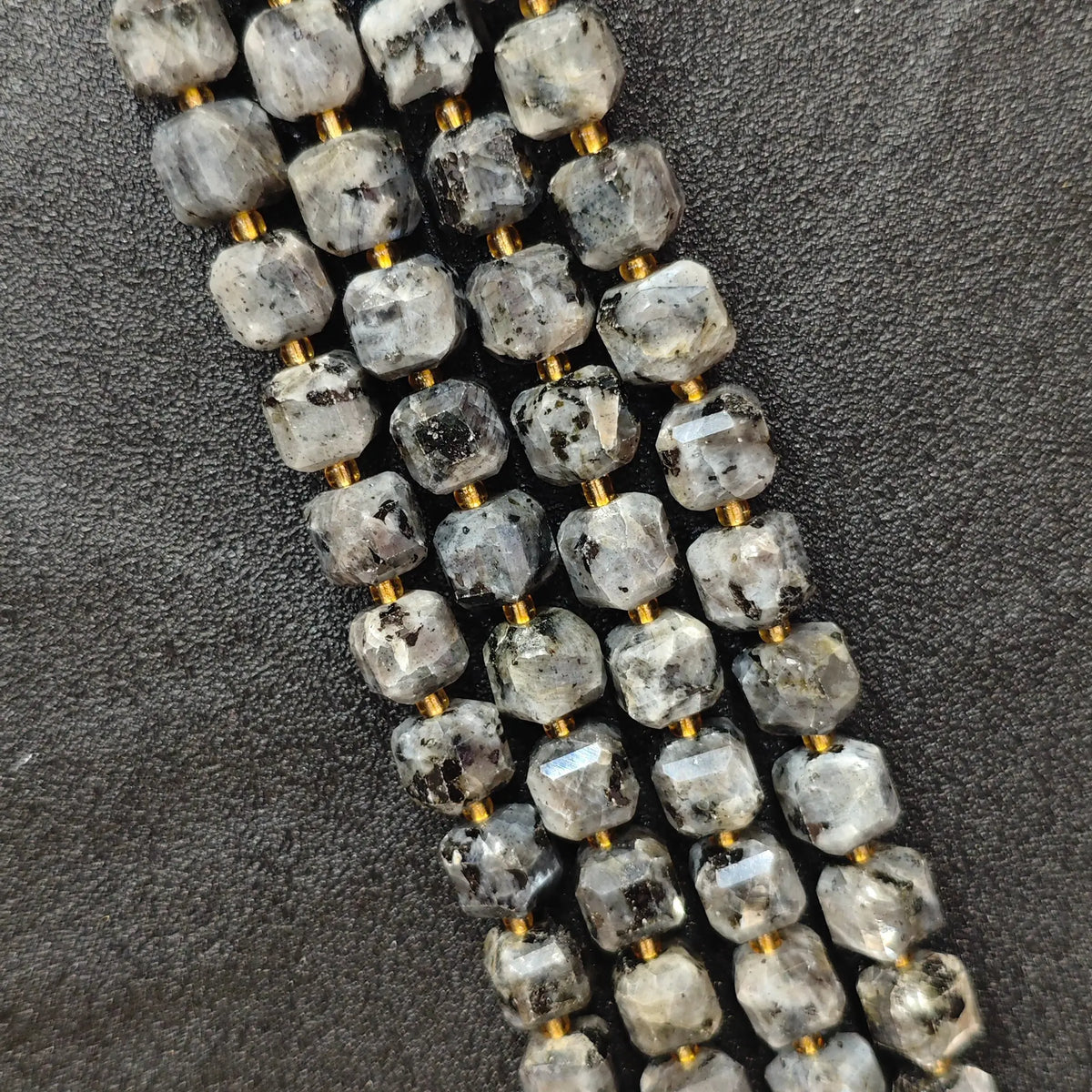 Close up of multi strands of natural black arfvedsonite soft-tumbled geometric cube beads showing overall strand layout