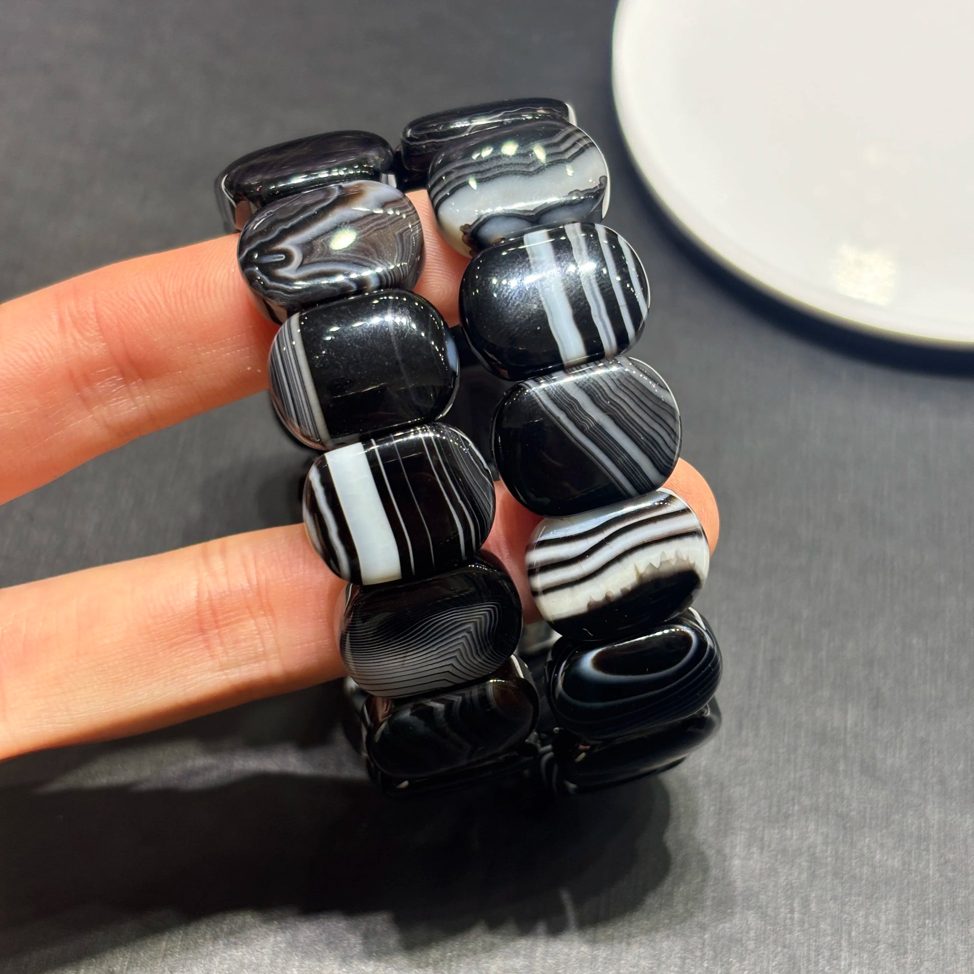 Black and white beaded bracelet held by a hand on a gray surface