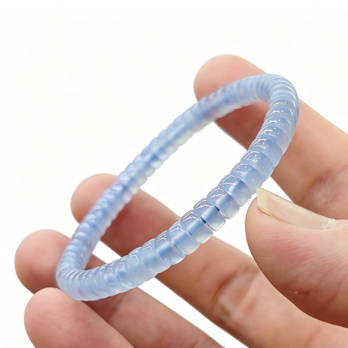 Close-up of mini blue agate tablet bracelet held in hand—showing translucency and smooth polished edges