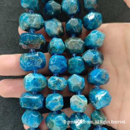 Hand displaying natural blue apatite faceted freeform beads showing vivid teal ocean color and pre-drilled center holes