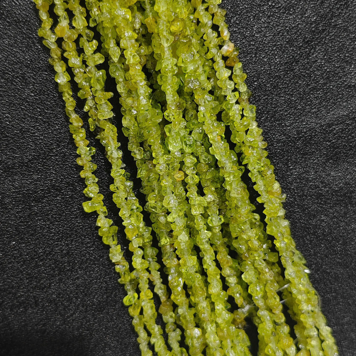 Multiple strands of natural peridot 4-6mm irregular green chip beads showing translucent brilliance[cite: 6]