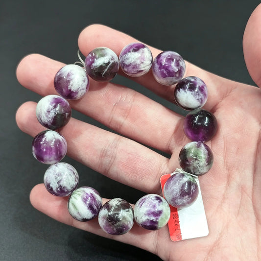 Large natural feather fluorite round bead bracelet displayed on hand showing chunky purple and white inclusions