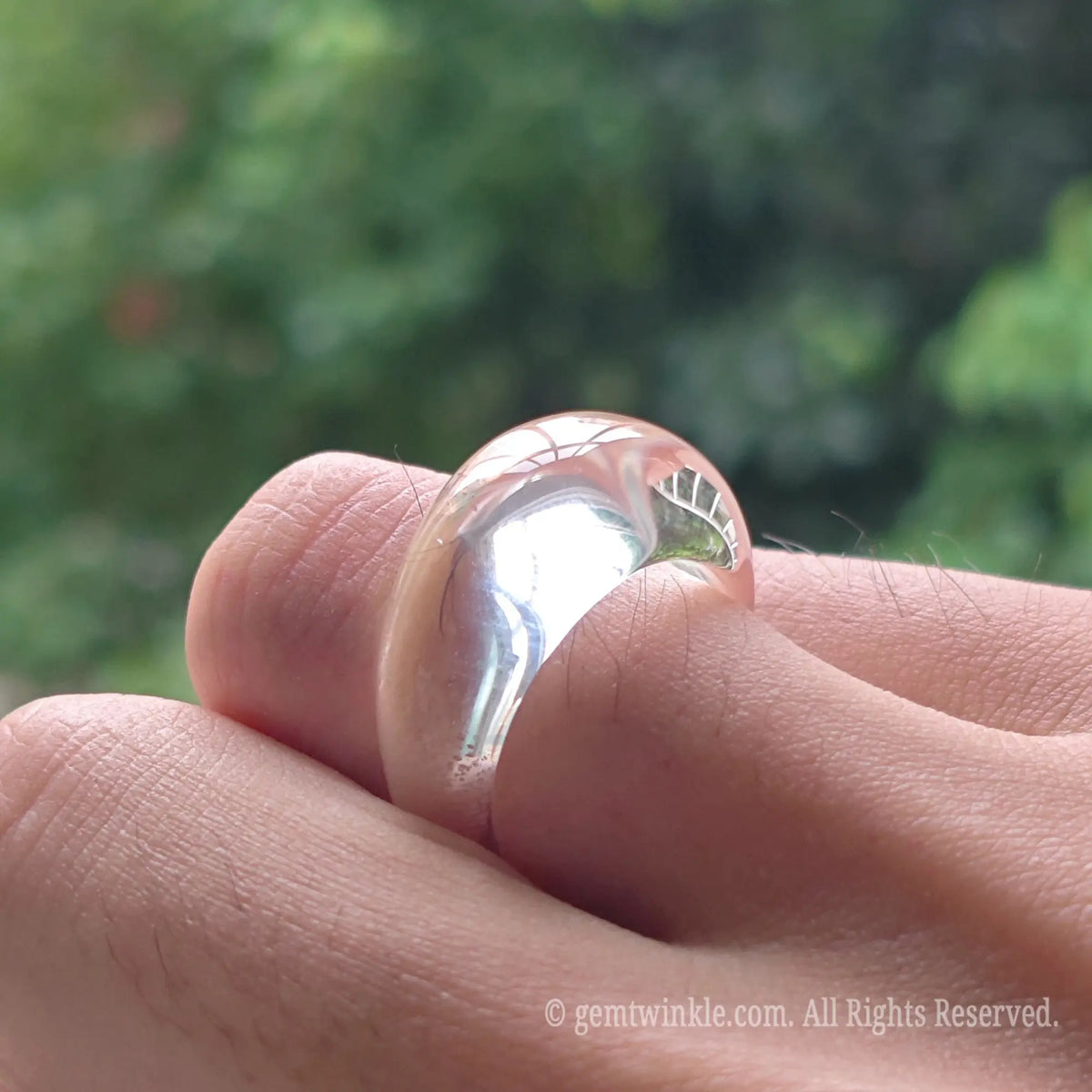 Close up view of transparent clear quartz ring resting on hand highlighting smooth inner and outer contour