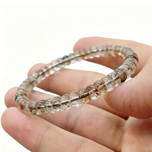 Mini clear quartz tablet beads held horizontally—showing subtle cloud-like and amber inclusions in translucent stone