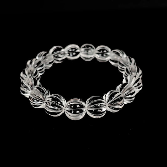Natural clear quartz pumpkin-shaped bead bracelet laid flat on black background, showcasing full circle design and faceted transparency