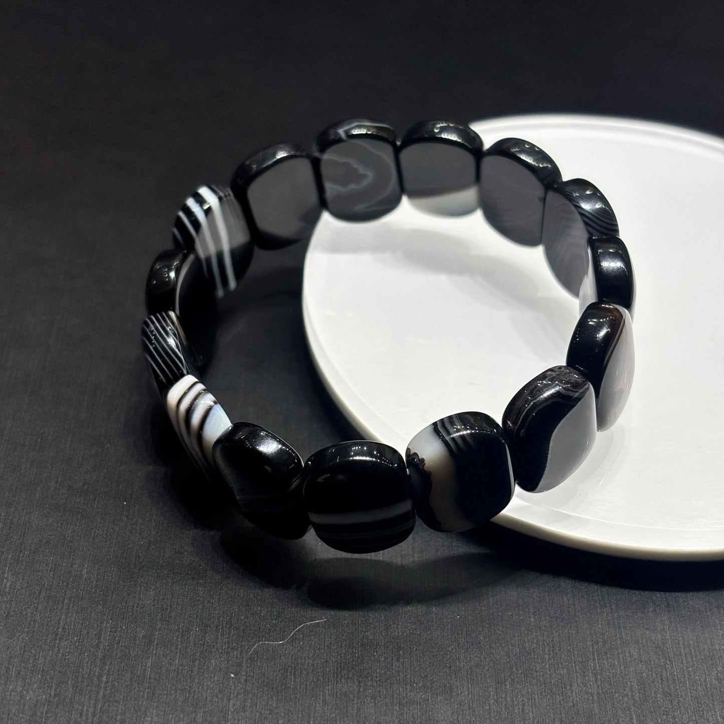 Close-up of natural black and white banded onyx square beads, polished geometric edges and parallel banding pattern