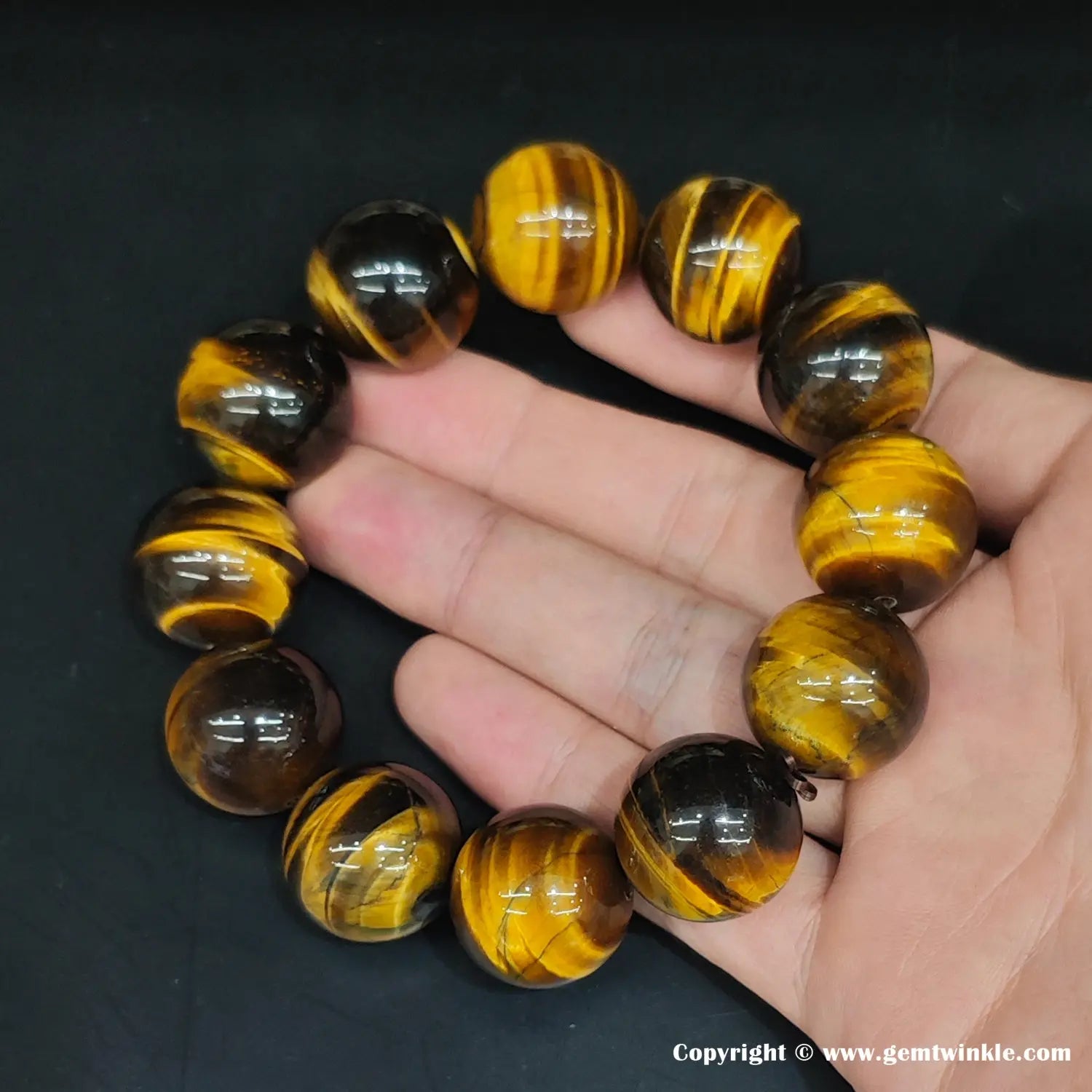 Macro detail of a ~14mm yellow tiger’s eye round bead. The lustrous finish creates clean reflections, highlighting the natural amber-striped pattern across the curved surface.