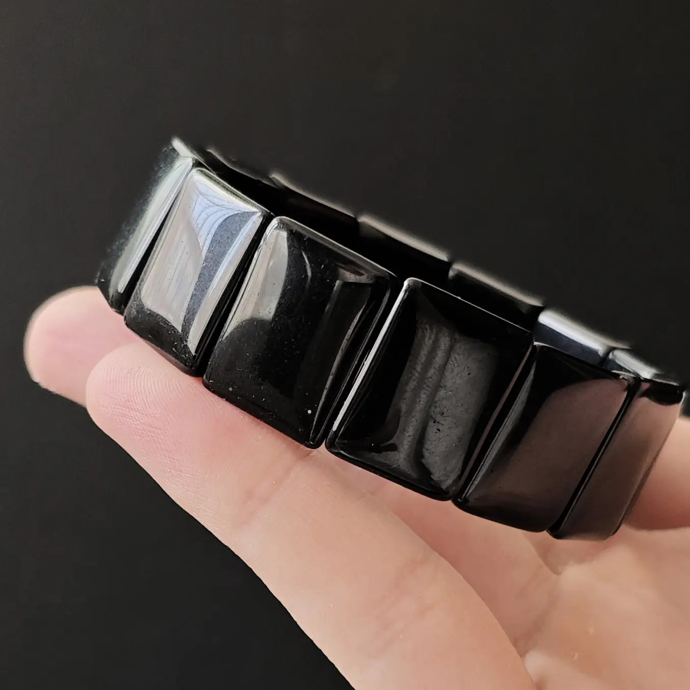 Close-up of black obsidian square beads showing smooth polished surface and natural luster