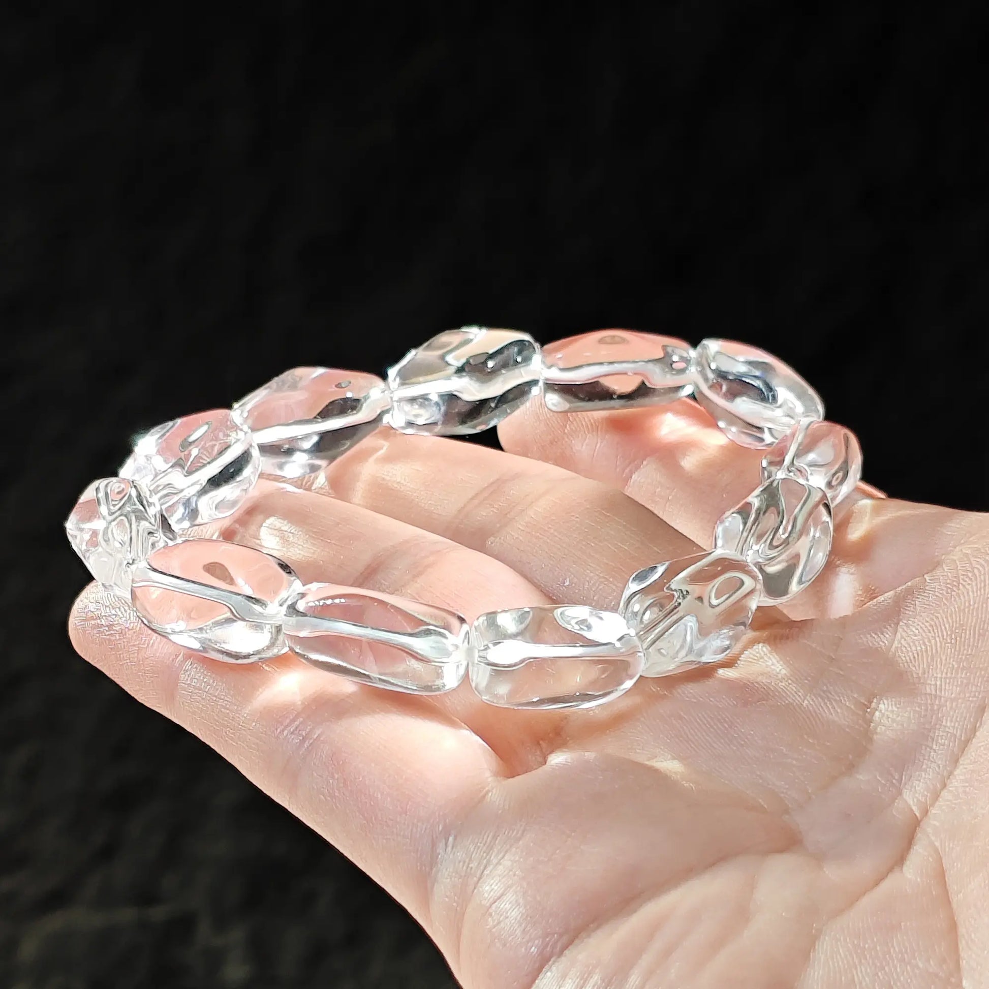 Detailed view: high-clarity clear quartz bead with subtle internal texture, smooth polished surface, and natural asymmetry