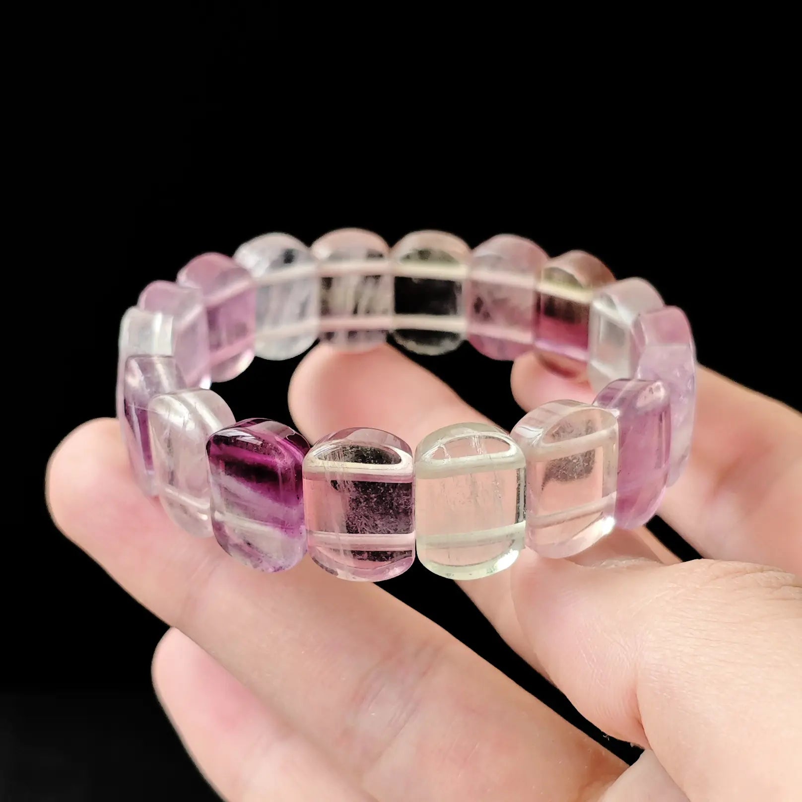 Close-up of natural fluorite oval beads with visible color zoning and polished facets, highlighting transparency and crystalline structure