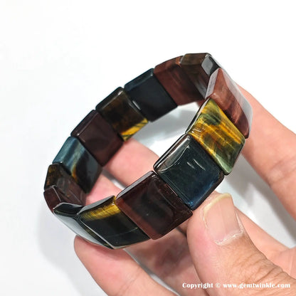 Hand displaying tiger eye bangle from side angle, emphasizing precise bead alignment, color zoning, and polished rectangular facets for retail display
