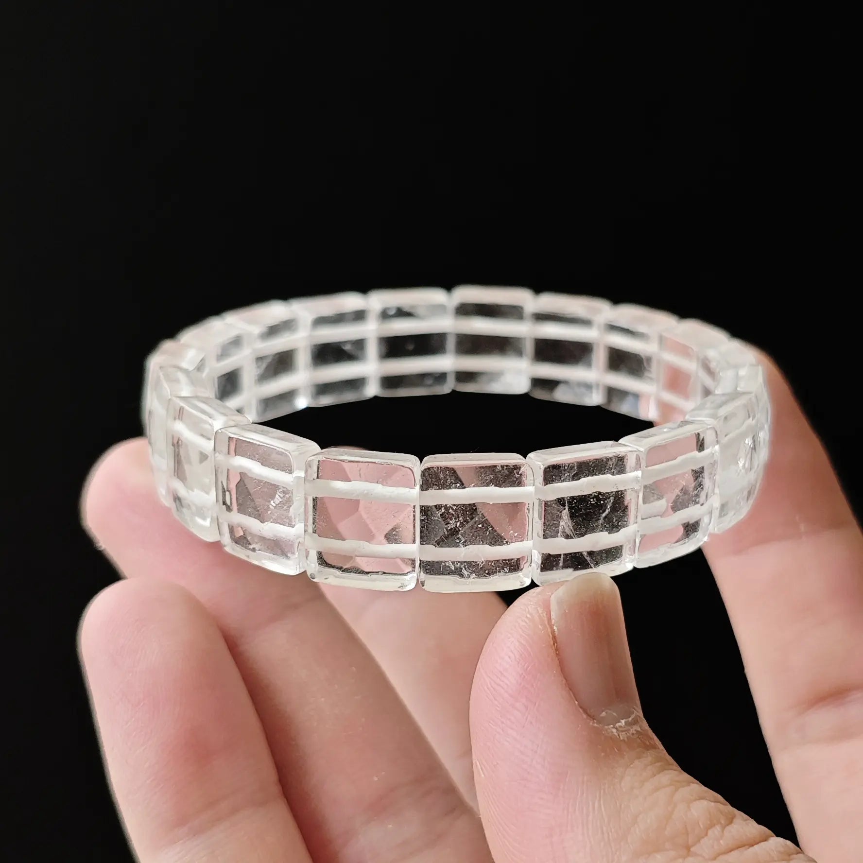 Macro: single clear quartz faceted bead with sharp geometric cuts, minor natural inclusions (ice-like), no cloudiness