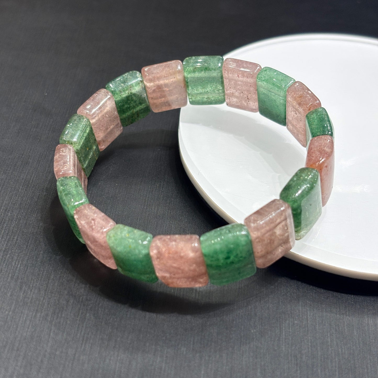 Close-up of natural pink and green strawberry quartz slab beads, showing fibrous inclusions and polished edges, handmade