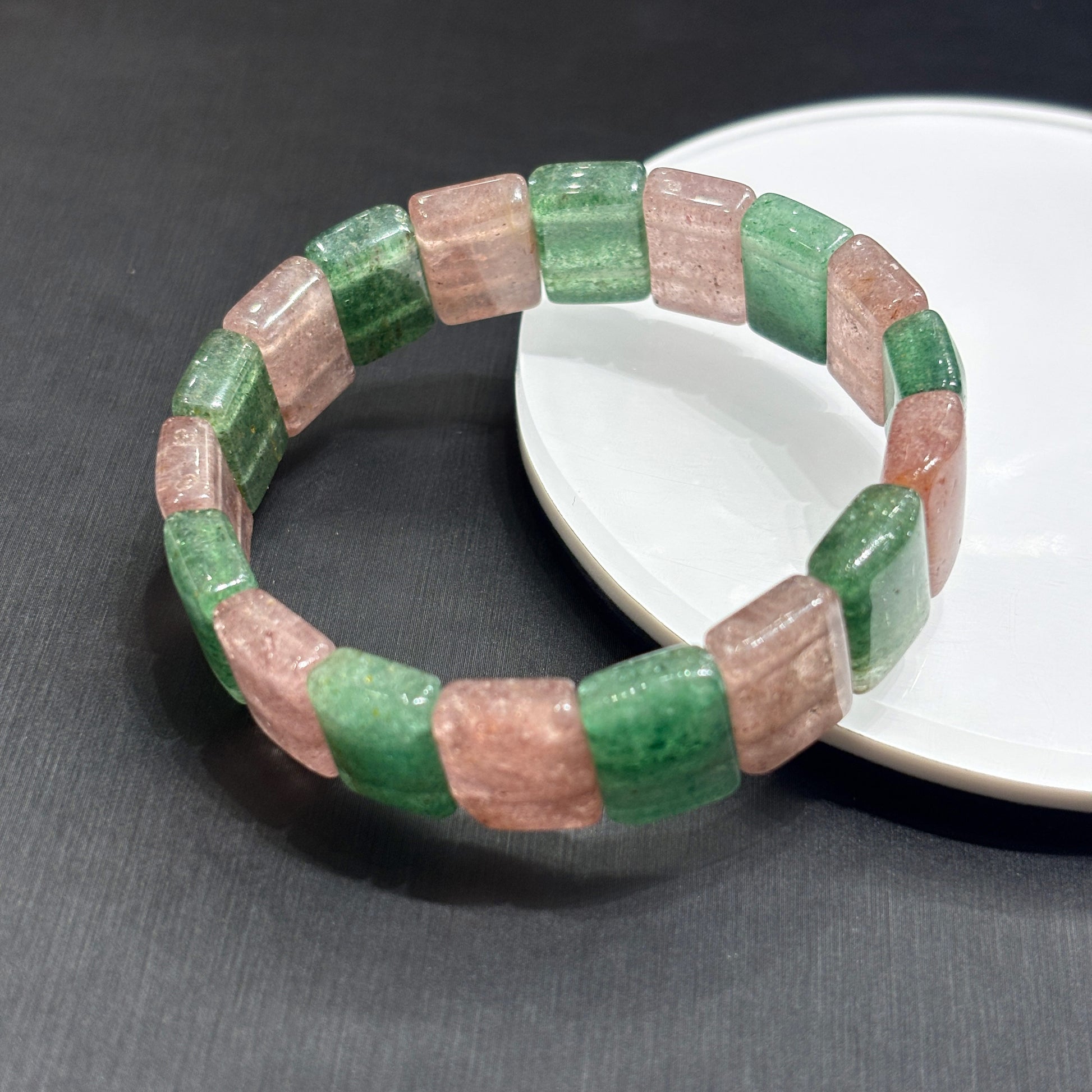 Close-up of natural pink and green strawberry quartz slab beads, showing fibrous inclusions and polished edges, handmade