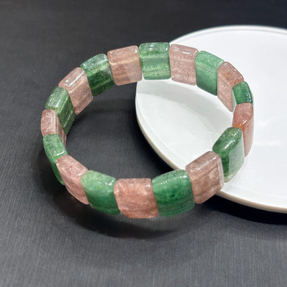 Close-up of natural pink and green strawberry quartz slab beads, showing fibrous inclusions and polished edges, handmade