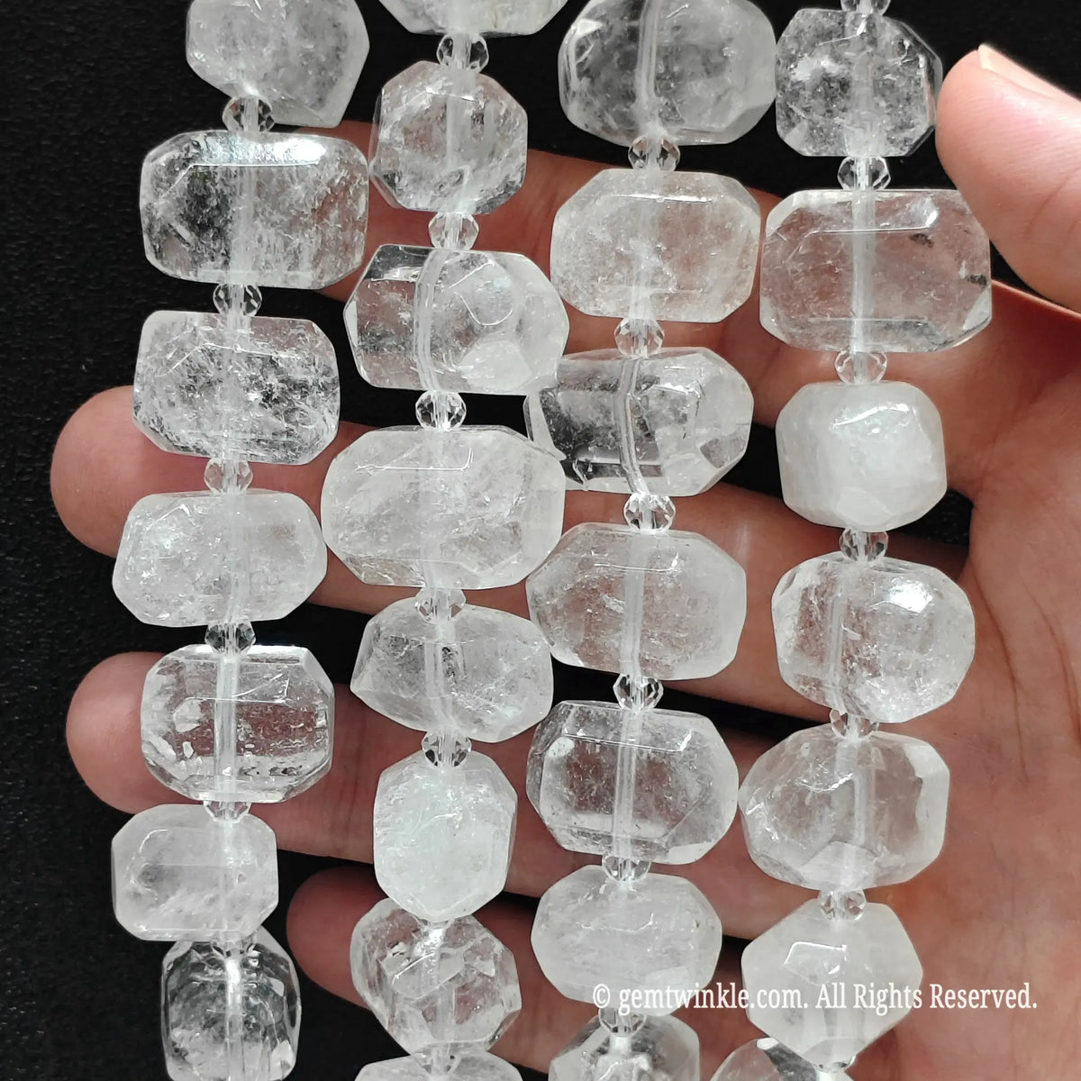 Finger pointing to an organic freeform milky white quartz bead displaying internal cloud veils and polished finish