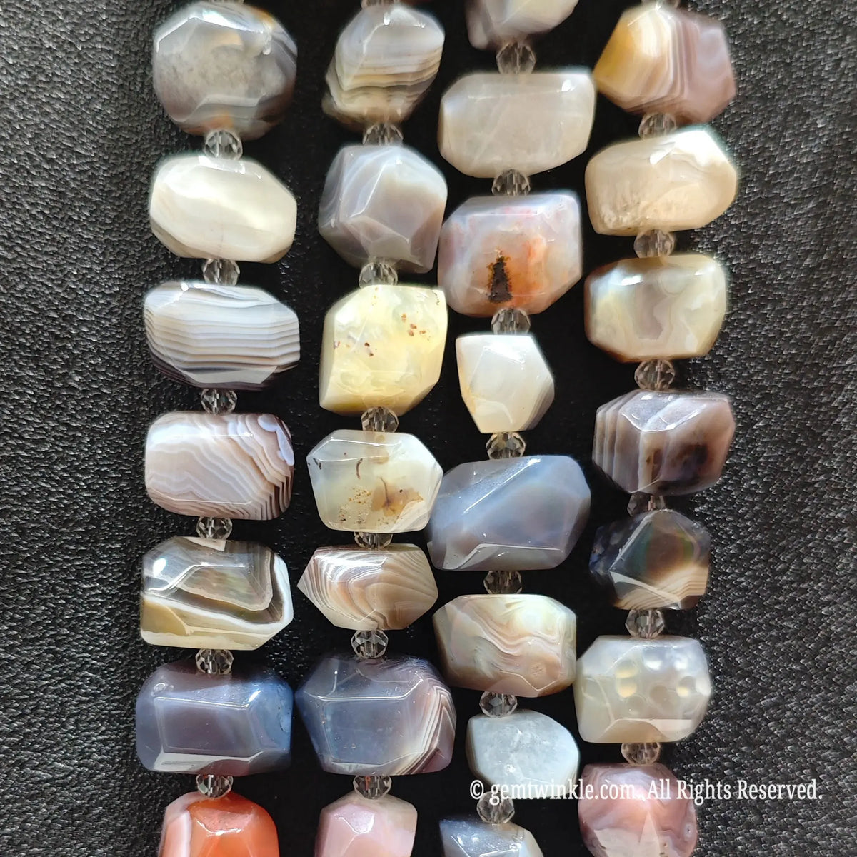 Finger pointing to a rough faceted crazy lace agate nugget bead displaying geometrical facets and natural concentric lace layers