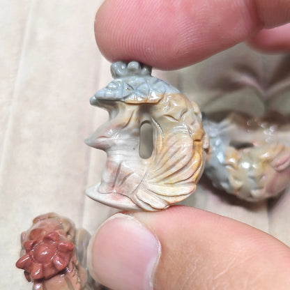 Side angle perspective of a small carved fox figurine forming a crescent arch posture with decorative tail details