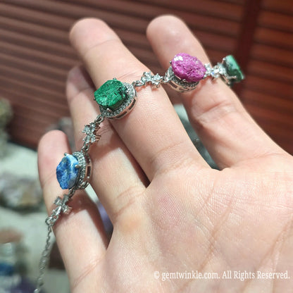 Angle view of a natural rainbow raw druzy link bracelet highlighting sparkling pink and blue crystal geode slices