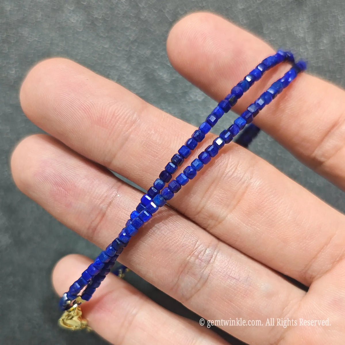 Detailed macro view of 2.5mm square cube Lapis Lazuli beads showing ultramarine blue stone with pyrite flecks