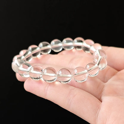 Collector-grade natural clear quartz bracelet with near-inclusion-free 10mm round beads; held in hand on black background, showcasing exceptional transparency and glassy luster for spiritual jewelry lovers