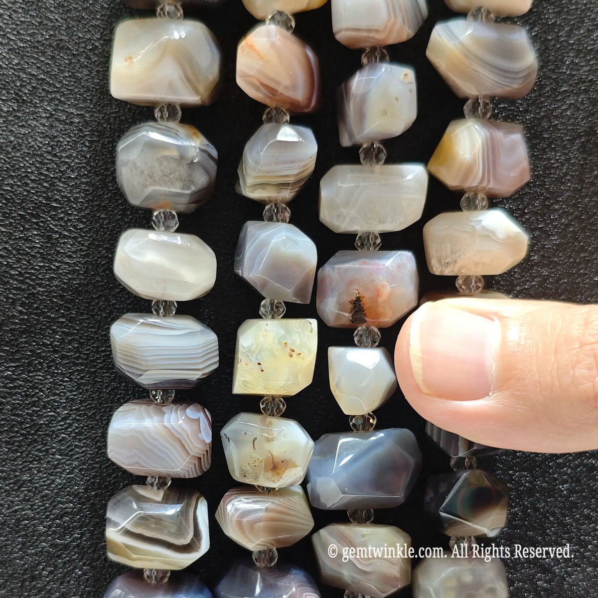 Hand showing large faceted crazy lace agate loose beads highlighting grey blue terracotta red and cream bandings